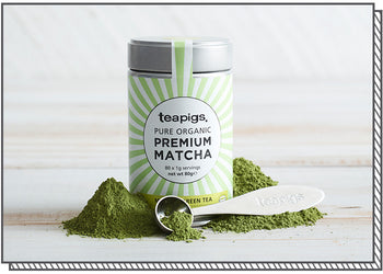 A tin of matcha surrounded by piles of rich green matcha tea